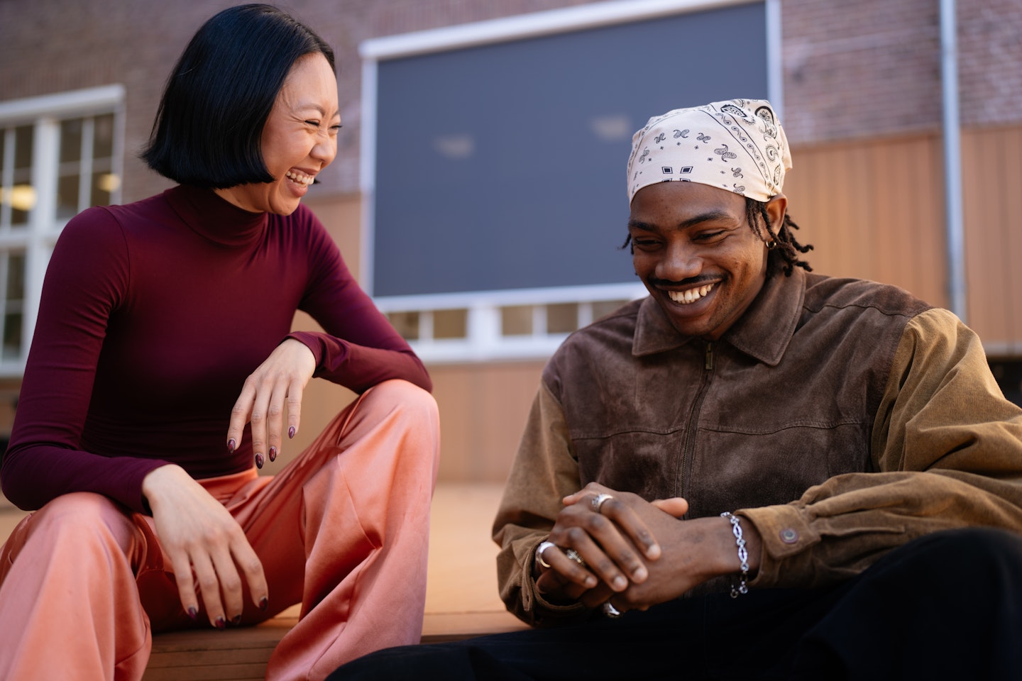 Twee mensen zitten buiten, hebben een gesprek en lachen