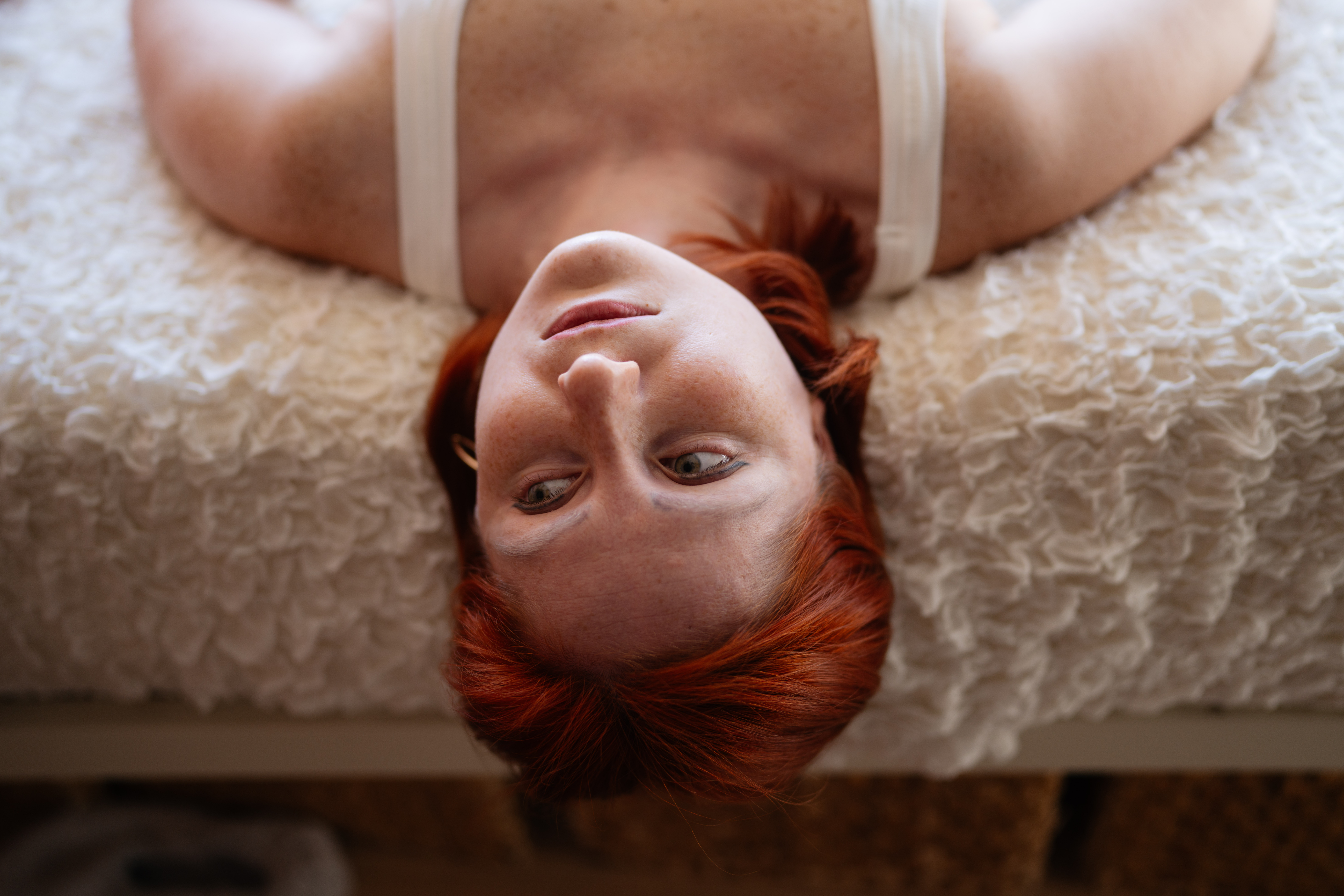 Een vrouw ligt rustig ondersteboven op haar bed en denkt na