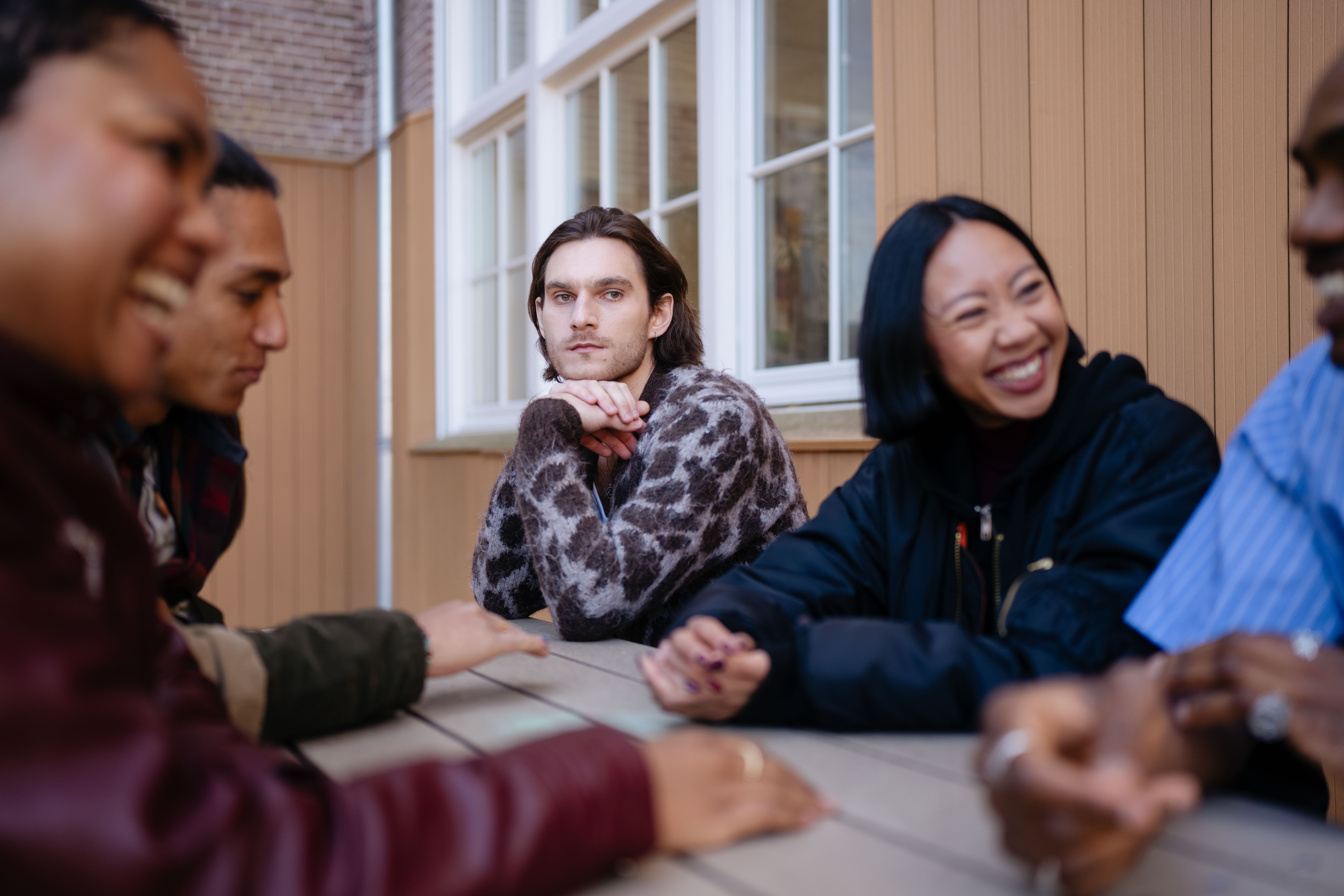 Man is alleen in gedachten verzonken aan een picknicktafel met gezellig kletsende vrienden