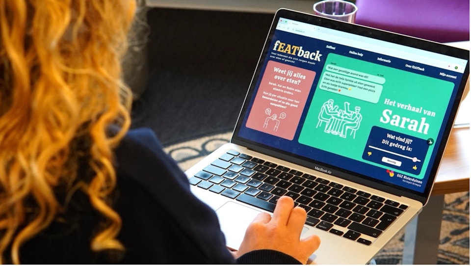 Een jonge vrouw zit achter haar laptop en kijkt naar het fEATback hulpprogramma.