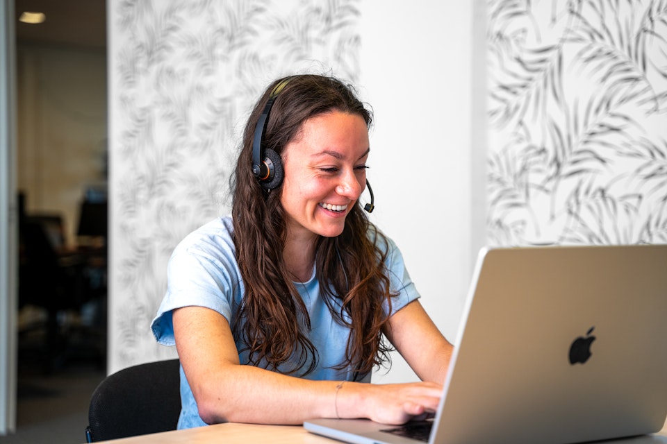 Vrijwilliger In je bol met headset achter een laptop