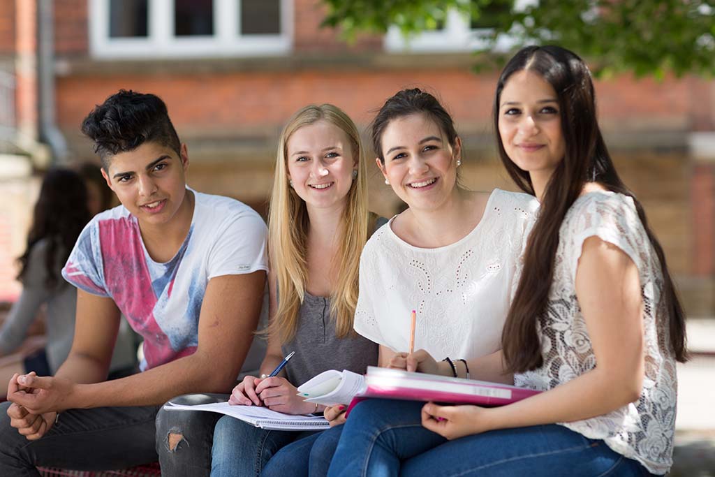 Vier jongeren kijken lachend in de camera
