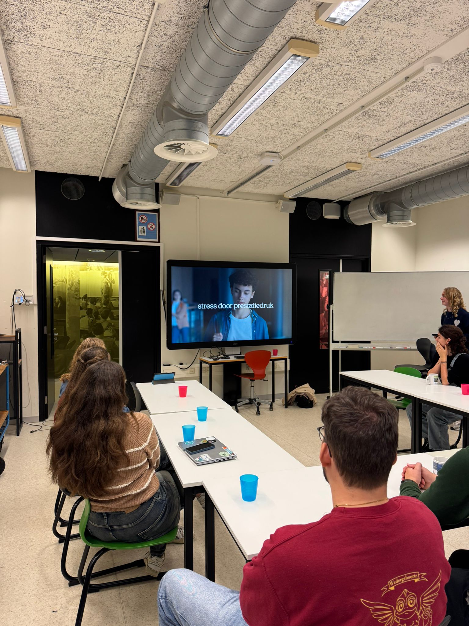 Klaslokaal waarin jongeren naar de video van In je bol kijken op een beeldscherm