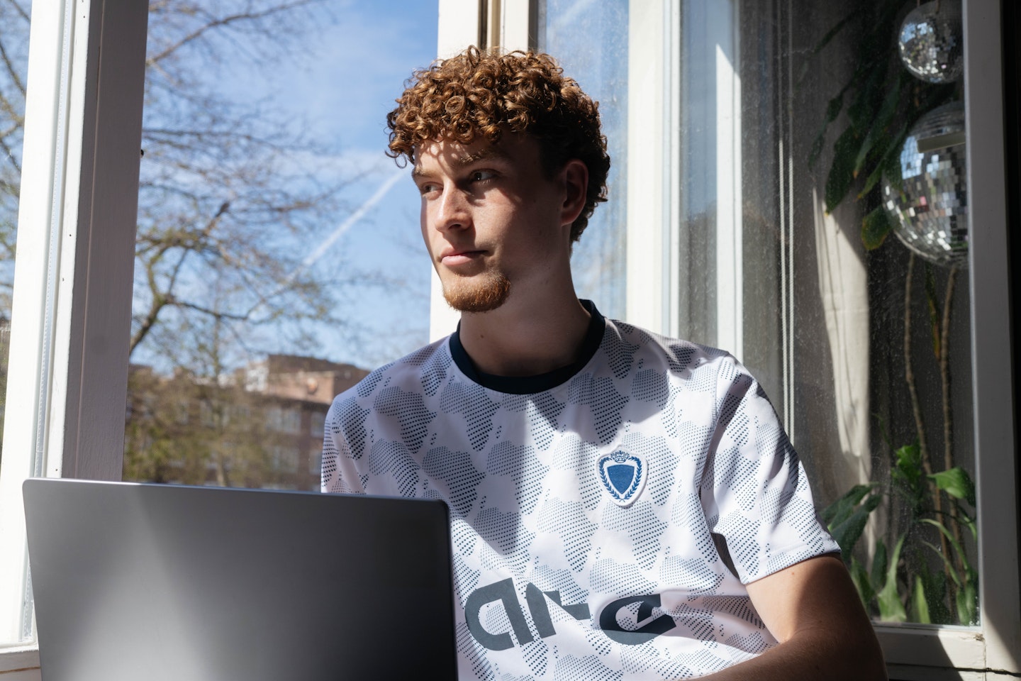 jongen-met-laptop-staart-uit-het-raam