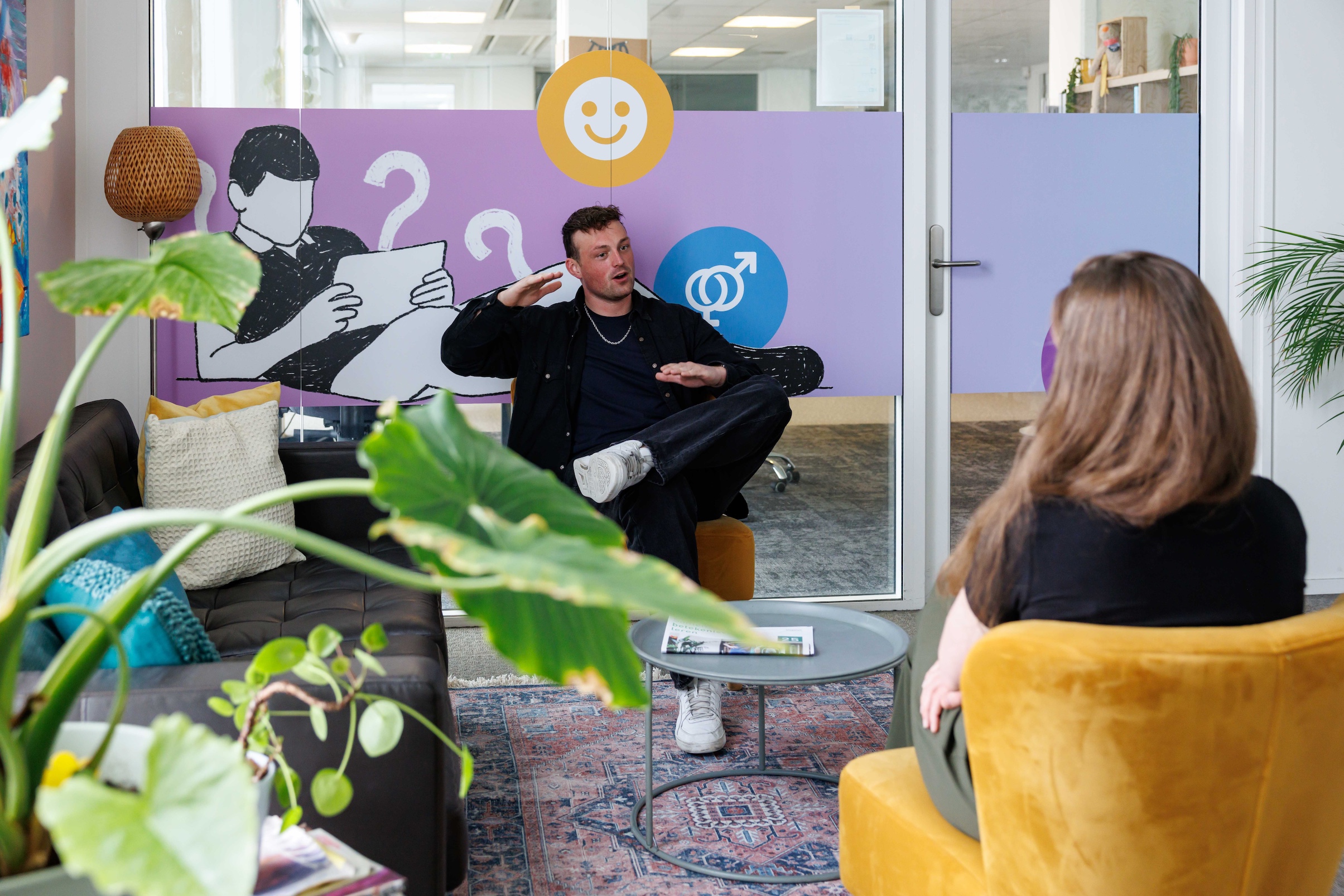 man en vrouw met elkaar in gesprek in huiskamersetting binnen kantoor In je bol