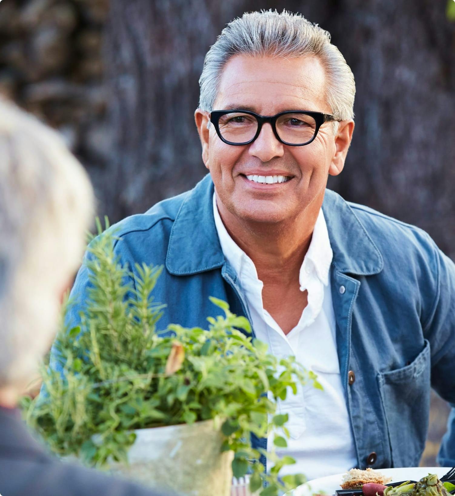 Middle-aged man smiling at another person.