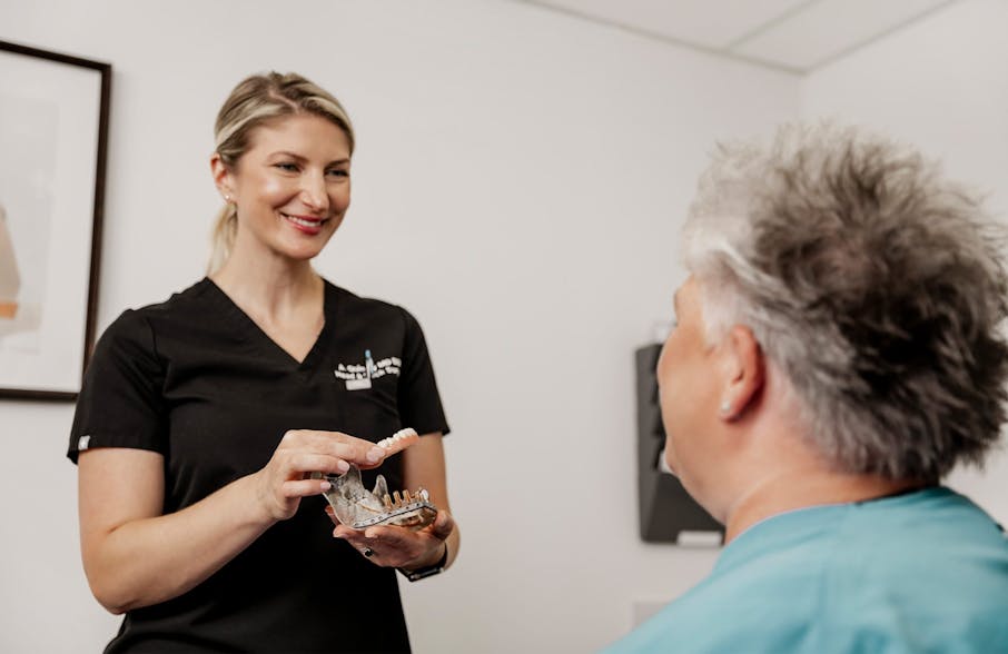 Dr. Quimby holding dentures to client