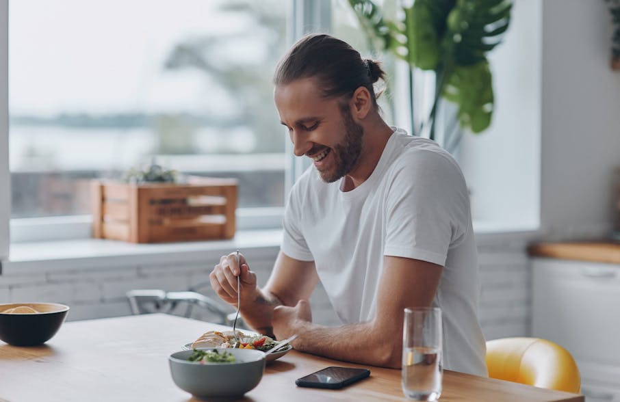 man with man bun eating meal at table