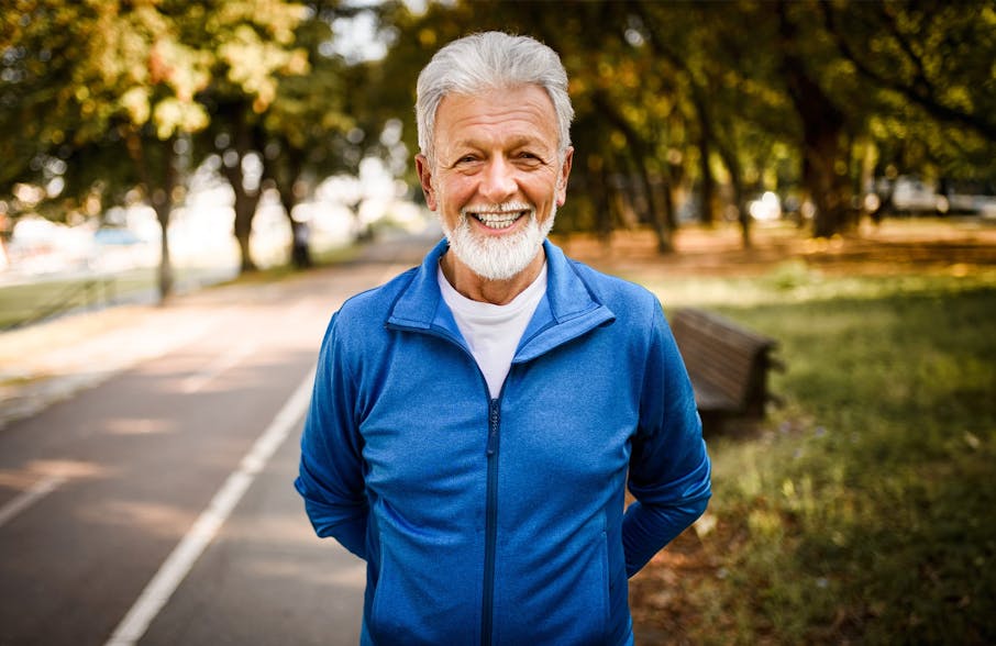 man with arms behind his back smiling