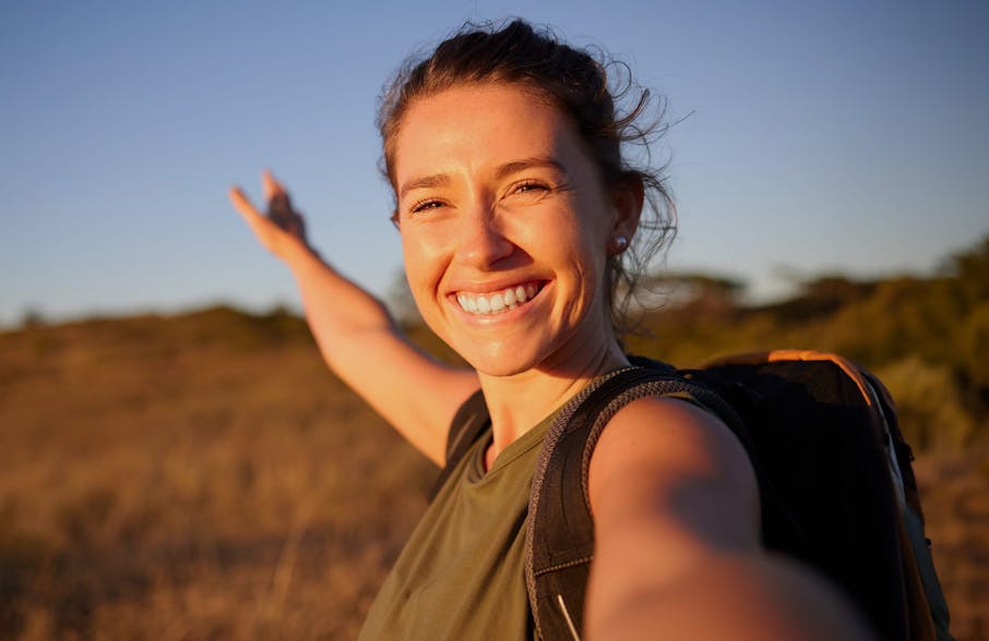 woman hiking taking a selfie with the sun hitting her