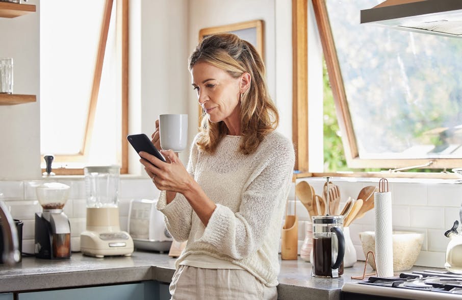 woman holding a mug with phone in the other hand
