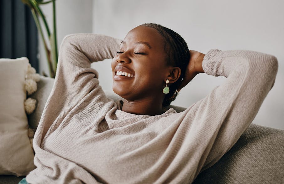 woman laying back on couch with hands holding her head up