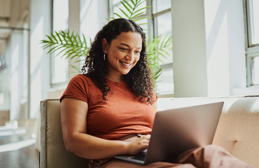 woman sitting on couch with laptop on her lap