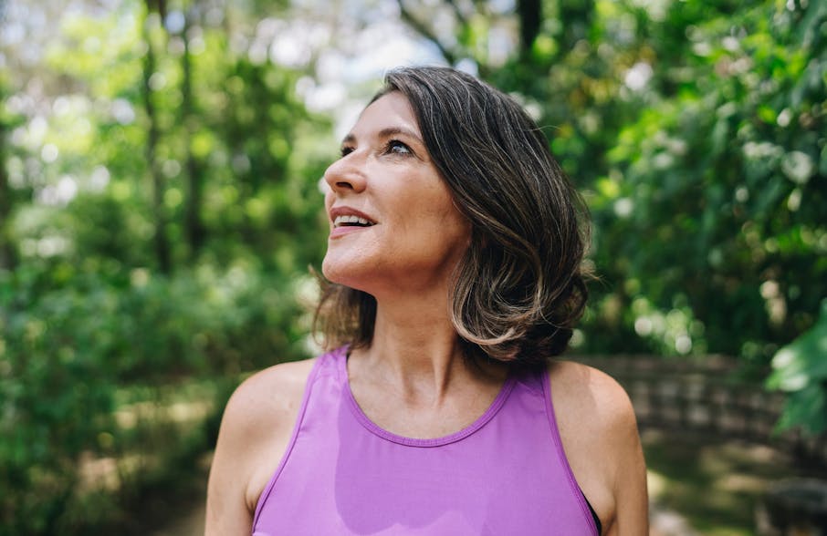 woman in forest jogging looking upwards