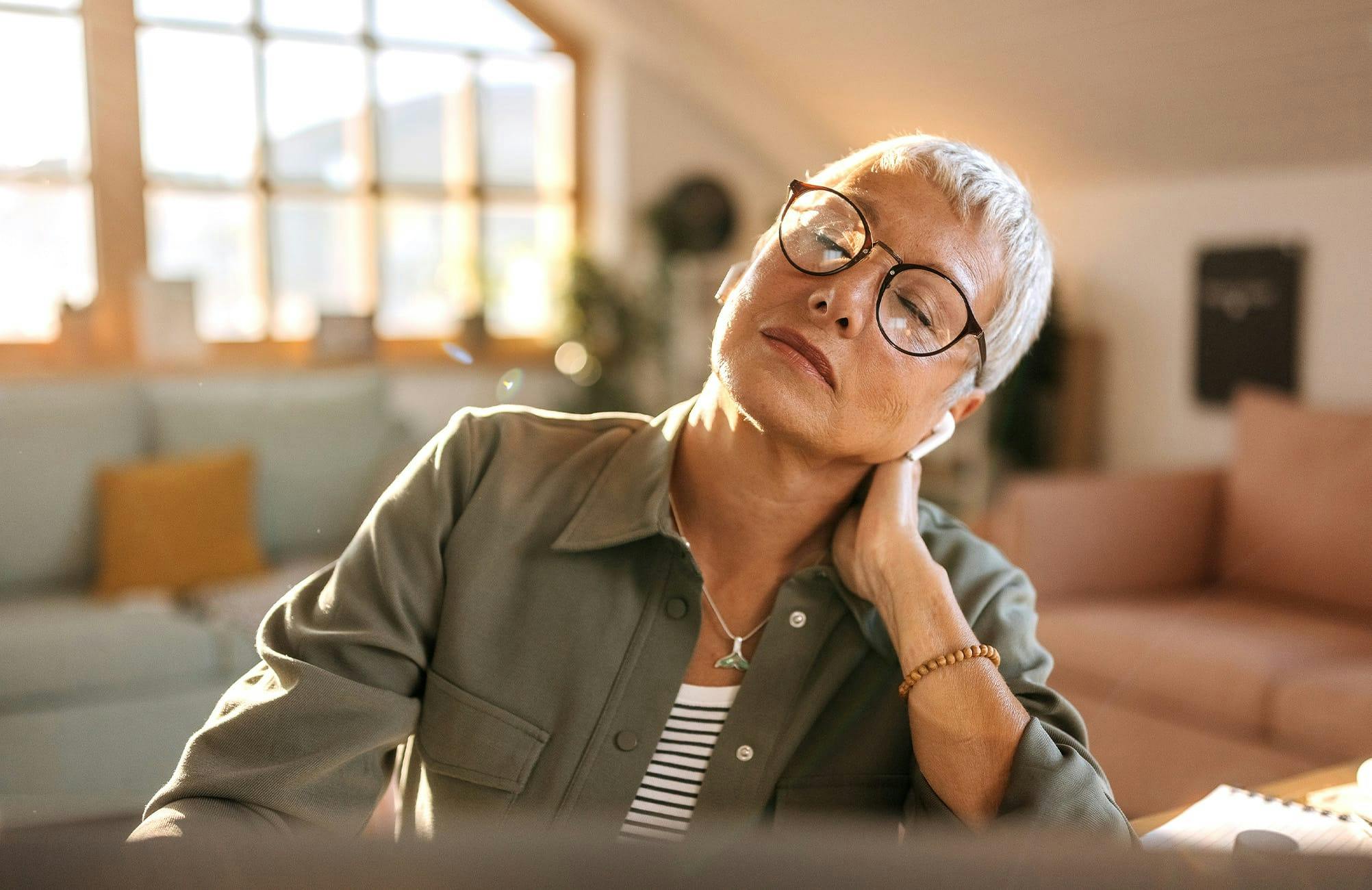 woman with short hair leaning on her hand thats touching her neck