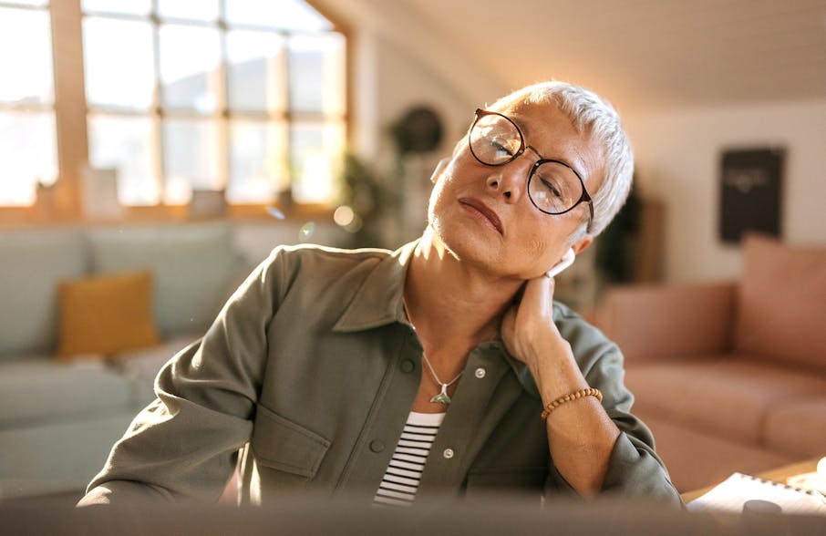 woman with short hair leaning on her hand thats touching her neck