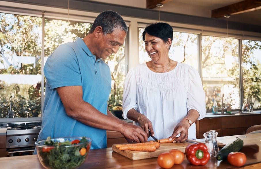 couple cutting carrots and cooking together