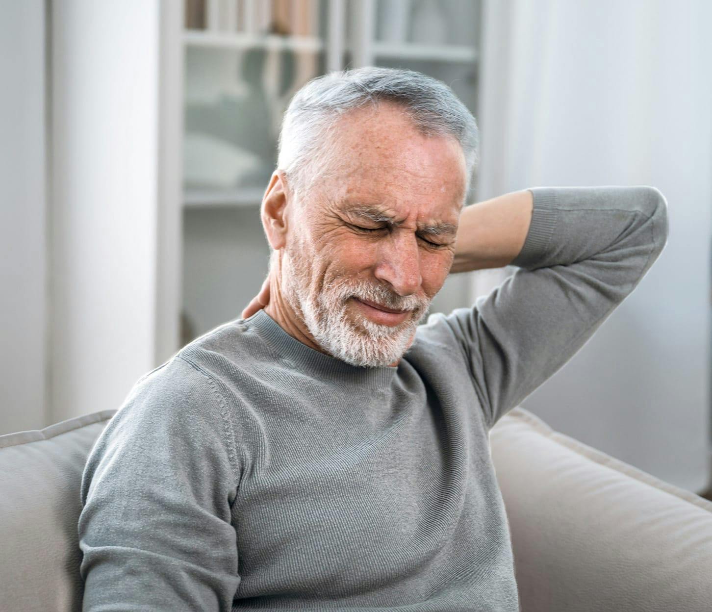 older man holding the back of his neck while in pain