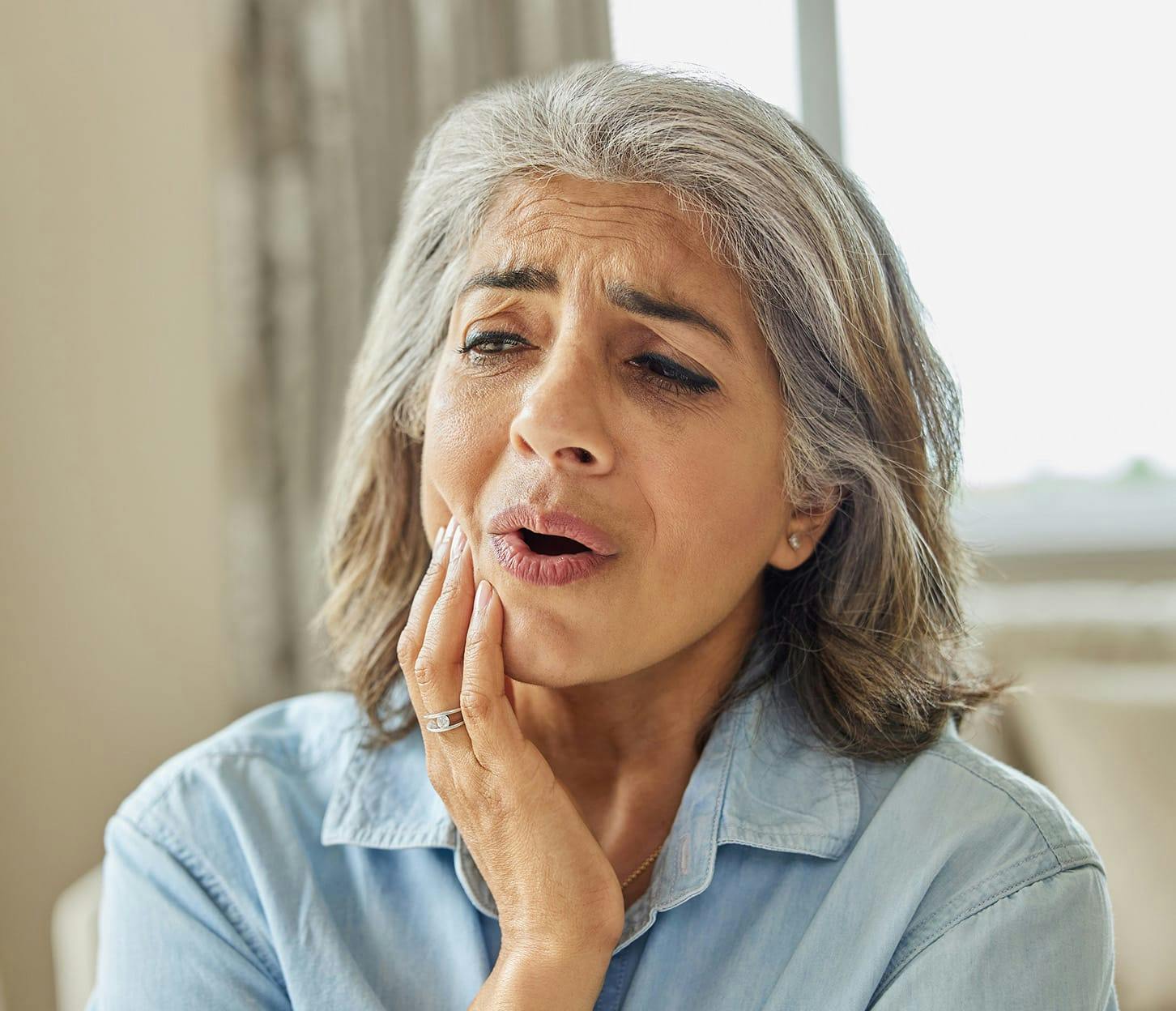 woman touching her cheek showing that her mouth is in pain