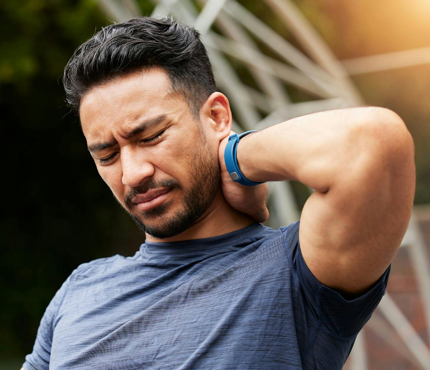 man grabbing the back of his neck in pain