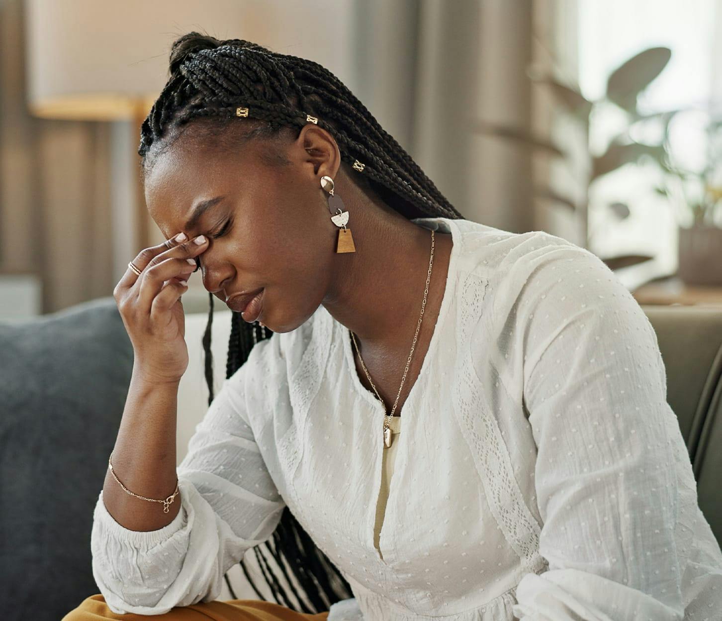 woman with her fingers on her forehead as she sits down