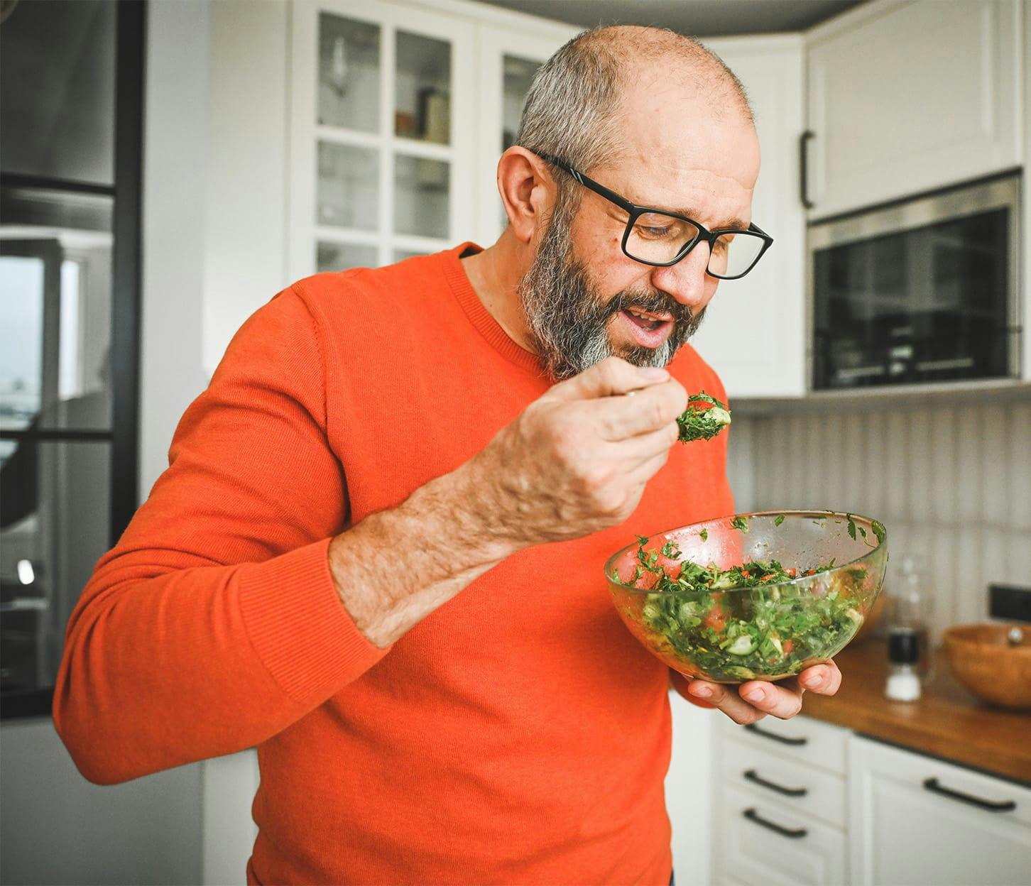 man eating a salad from a bowl