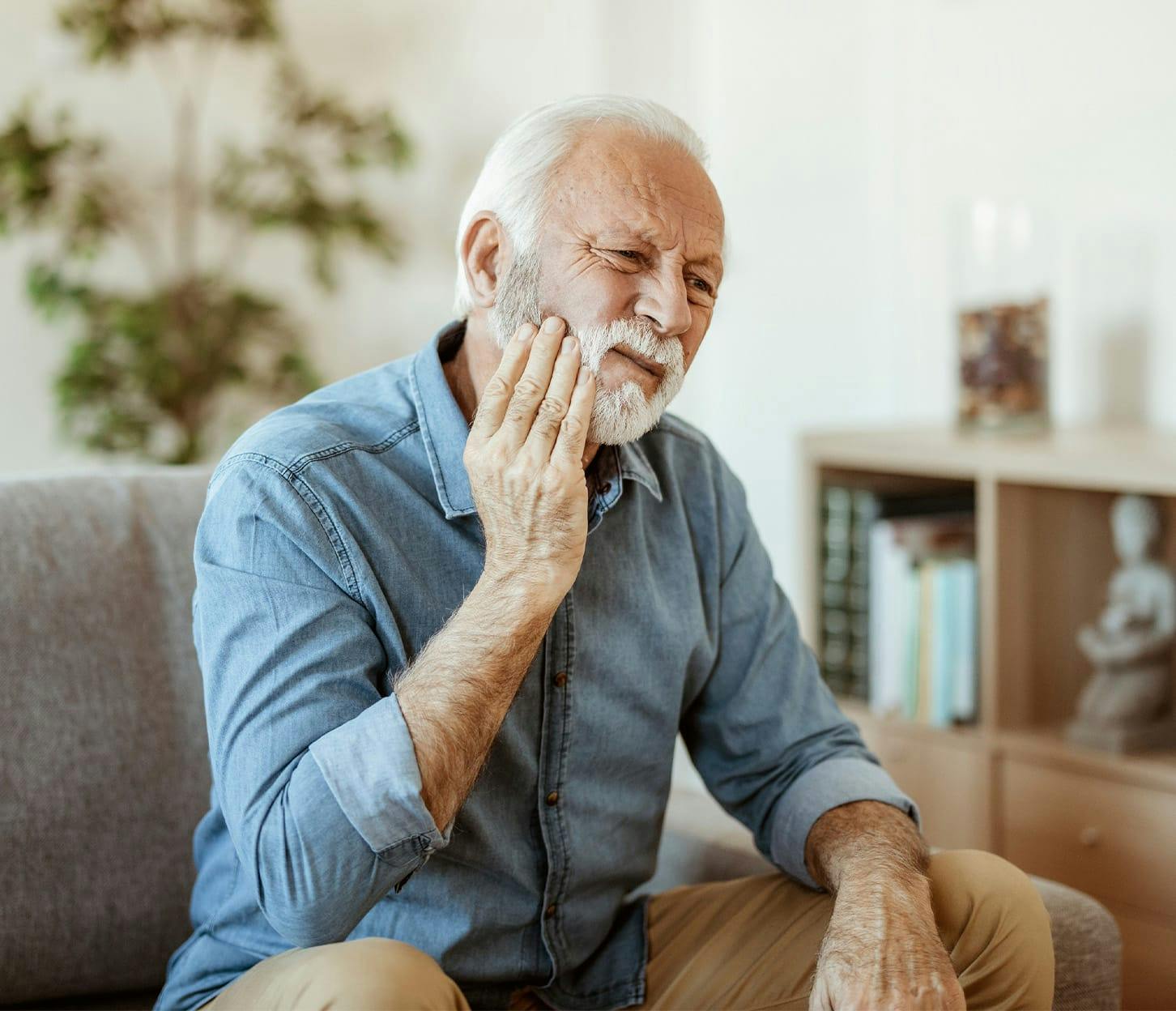 older man touching his jaw while sitting down