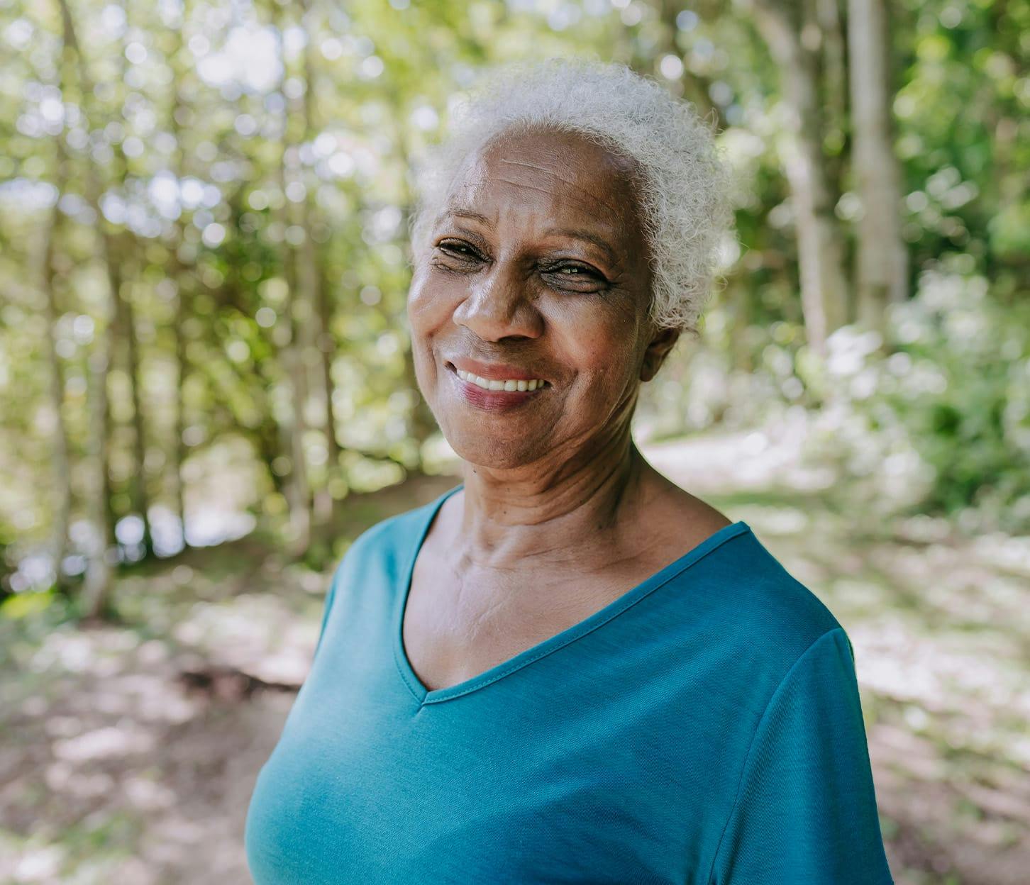older woman in forest in a blue shirt