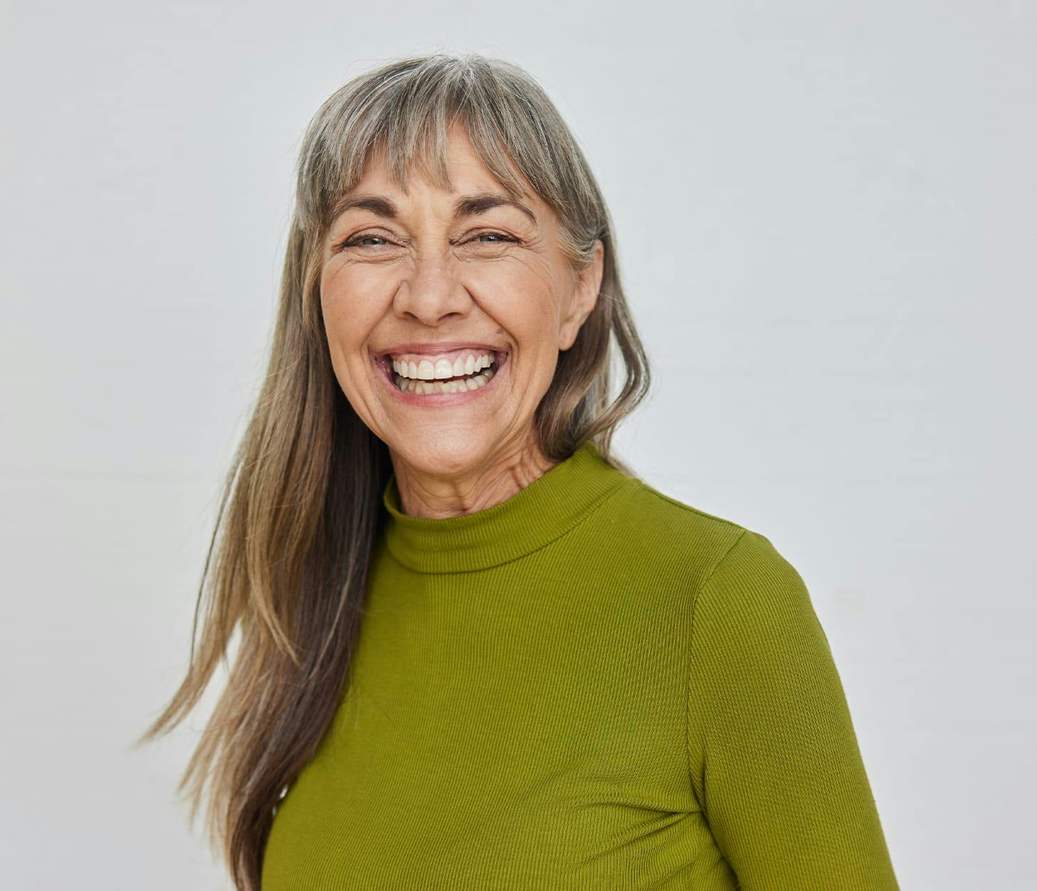 woman with bangs smiling with a green shirt on