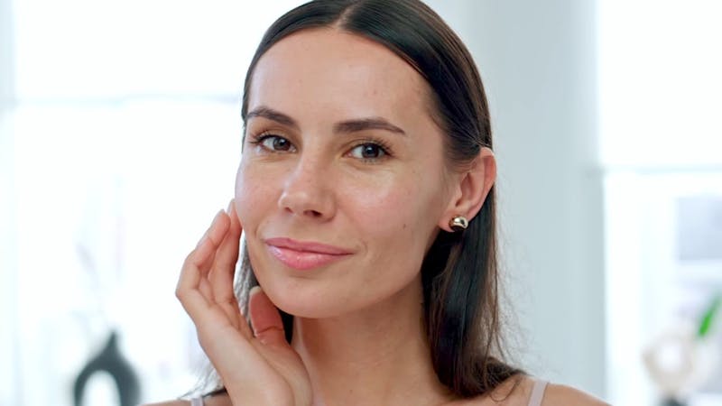 woman smiling and touching her cheek