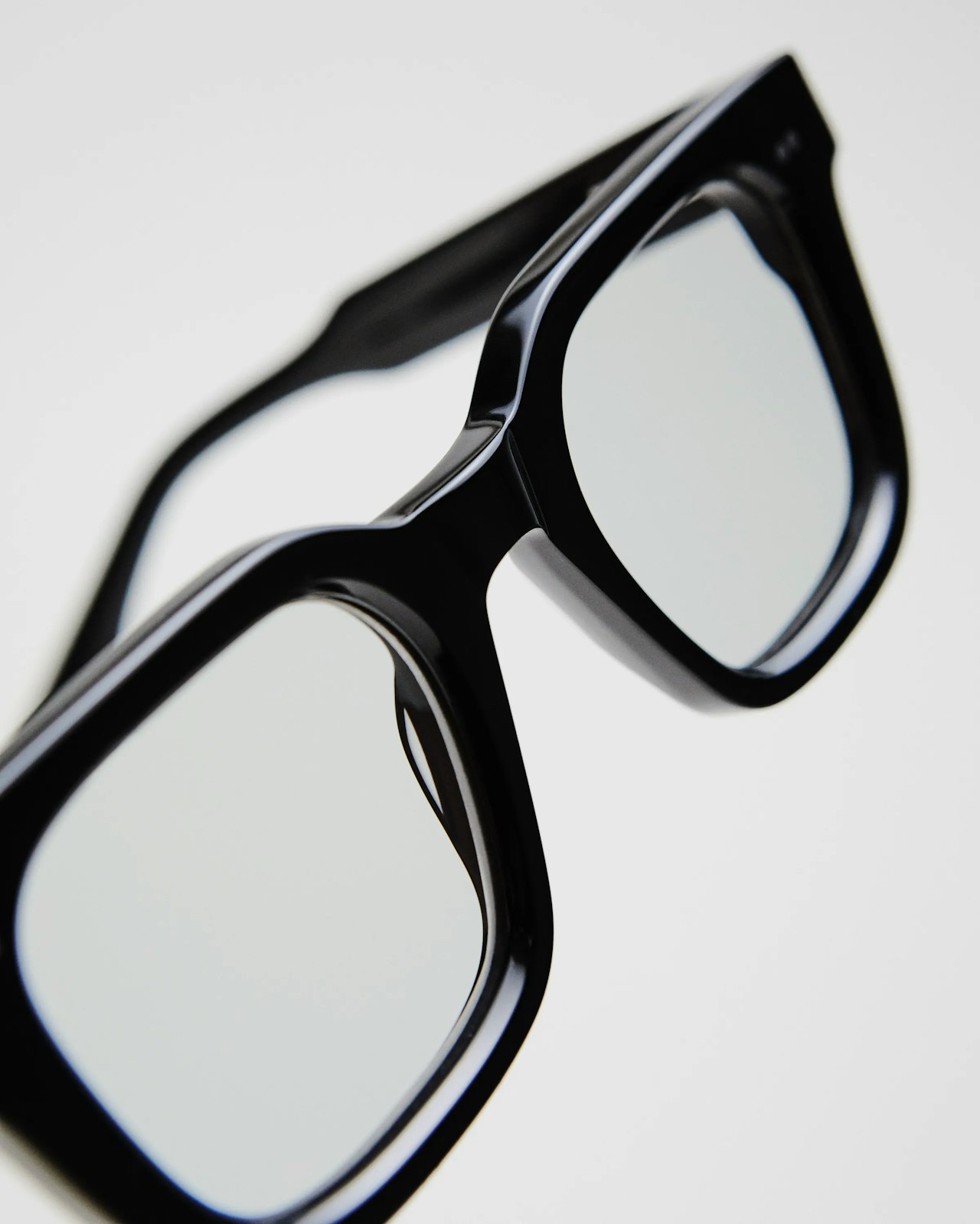 Black, thick-framed eyeglasses with clear lenses on a white background.
