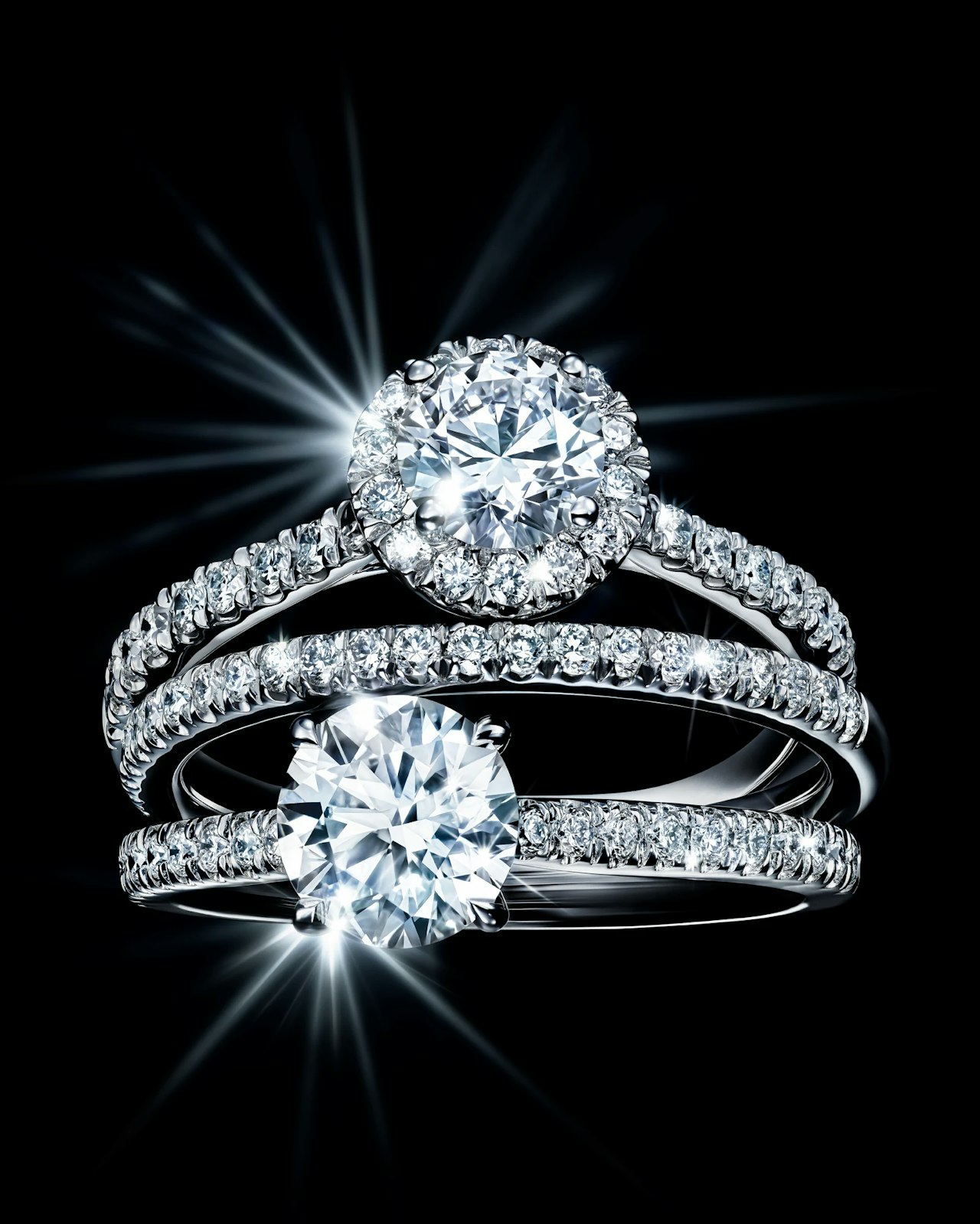 Three sparkling diamond rings with radiant, shining stones on a black background.