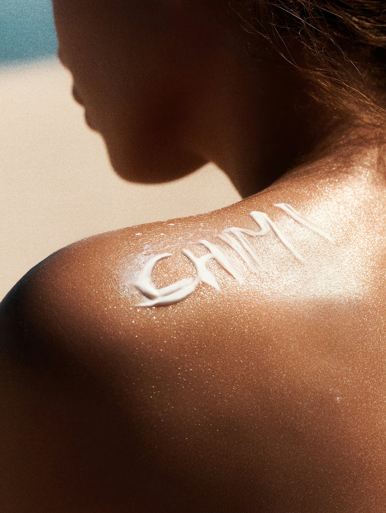 Sunscreen on a person’s shoulder spelling out CHIMI on sun-kissed skin.