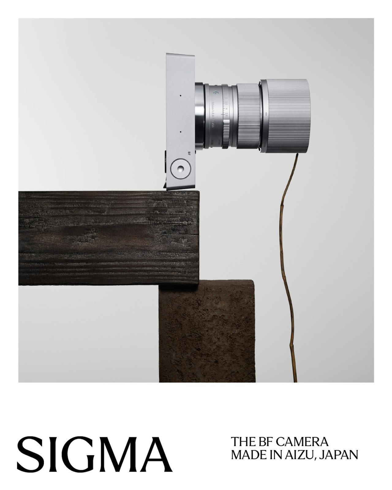 A silver camera balances on a wooden beam with a cord hanging down.