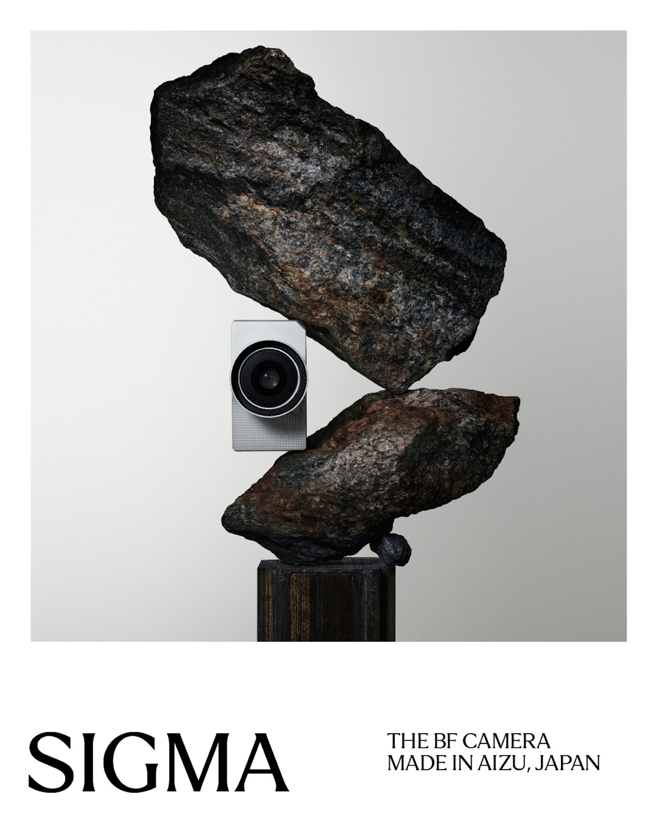A Sigma camera balanced between two stacked rocks.