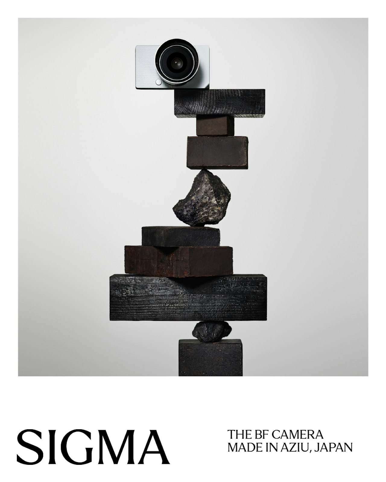 A Sigma camera balanced atop a stack of dark wooden blocks and stones.