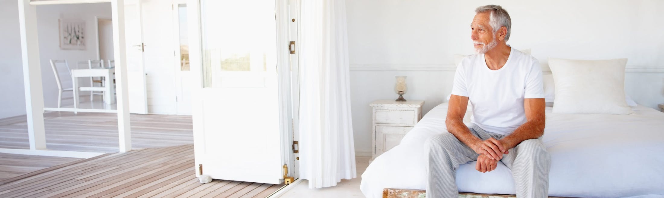man in white sitting on bed