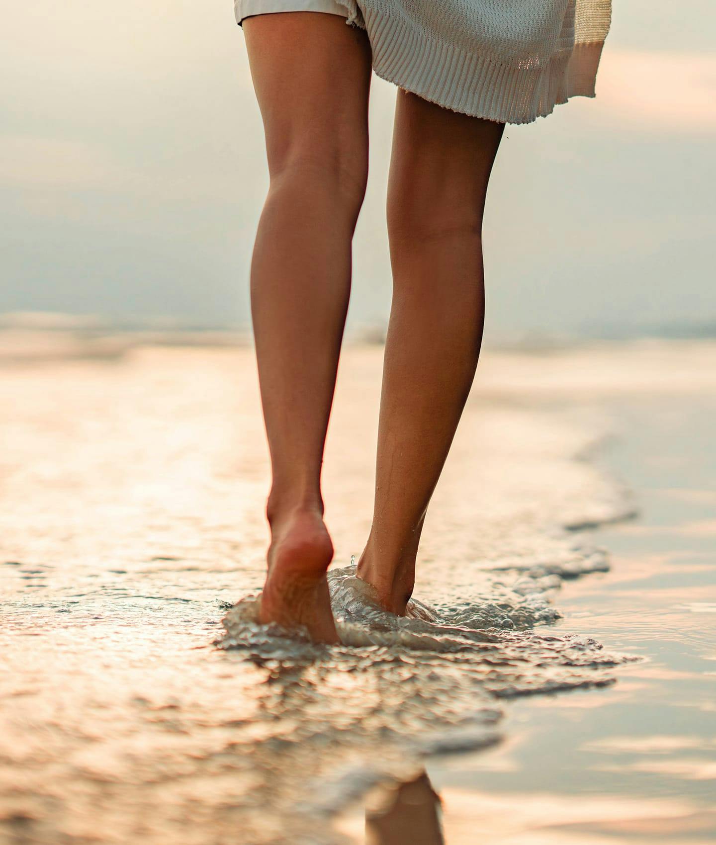 woman's legs walking in ocean