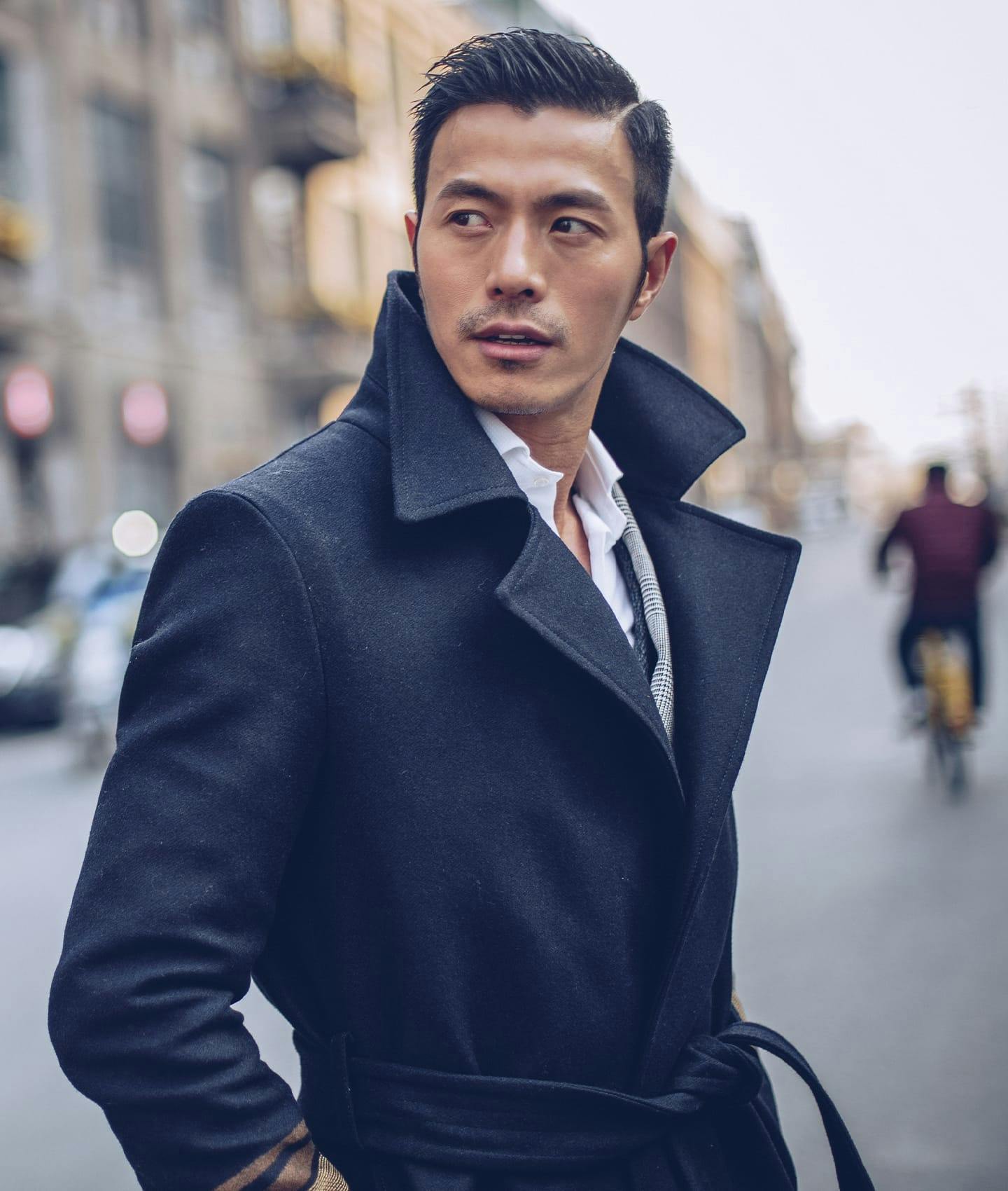 man in overcoat looking over shoulder