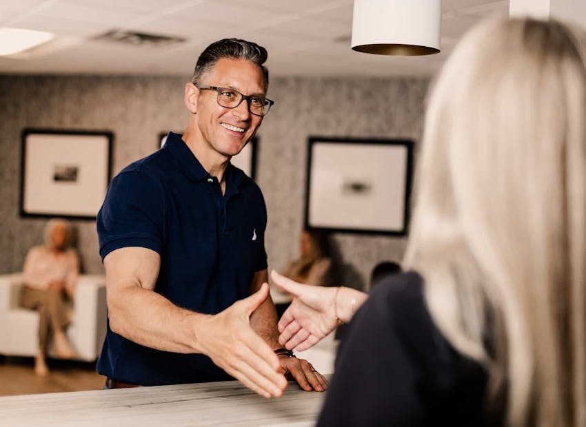 patient and front desk person shaking hands