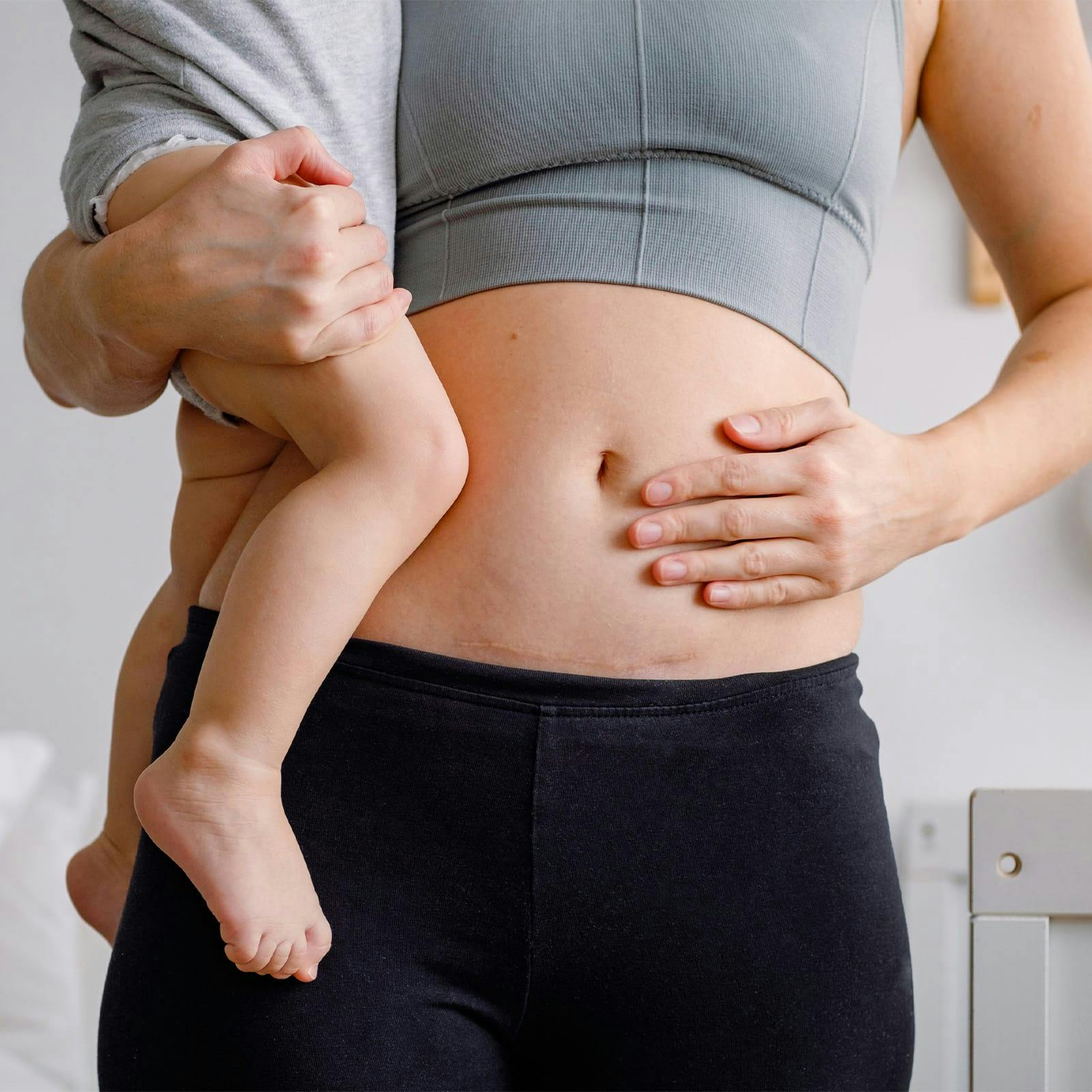 woman's stomach close up while she's holding toddler
