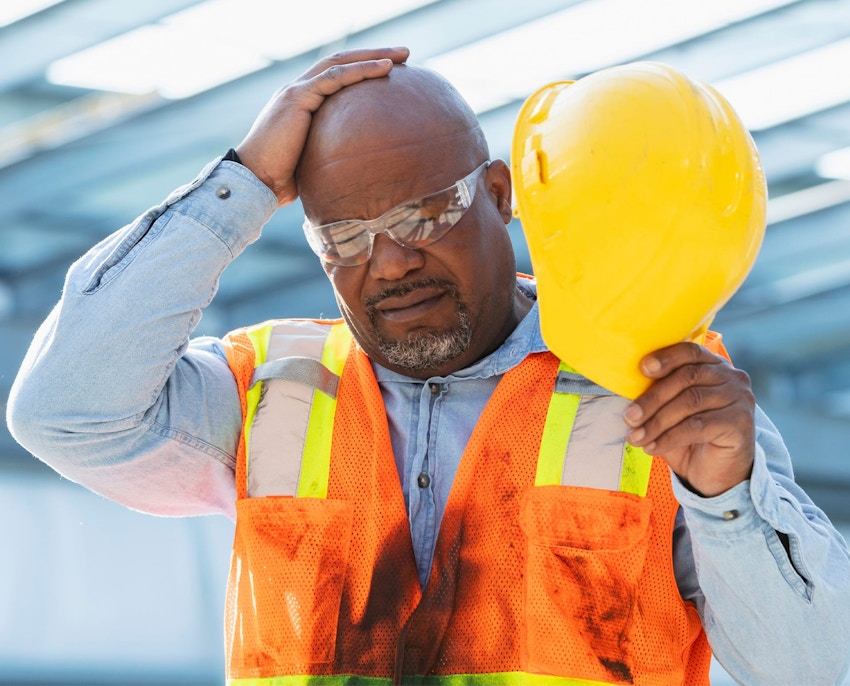 construction worker holding his hat and rubbing his head