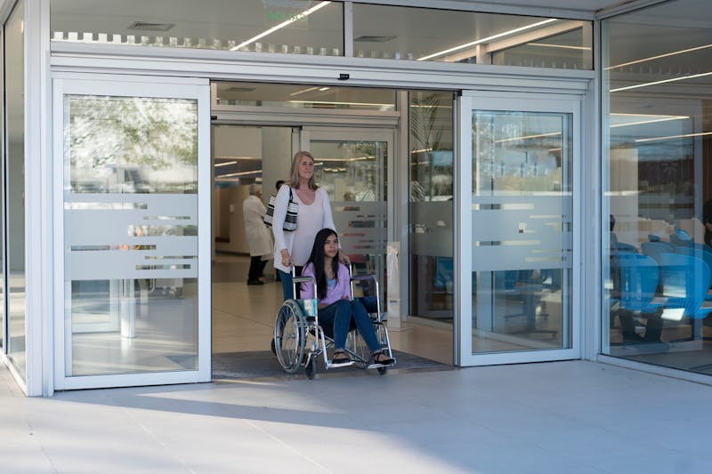 woman rolling teen girl from hospital in a wheelchair