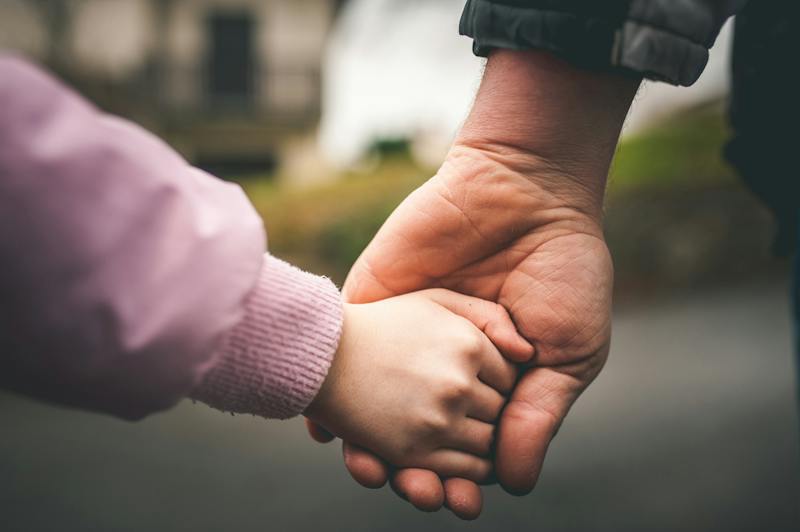 A child holding hands with an adult