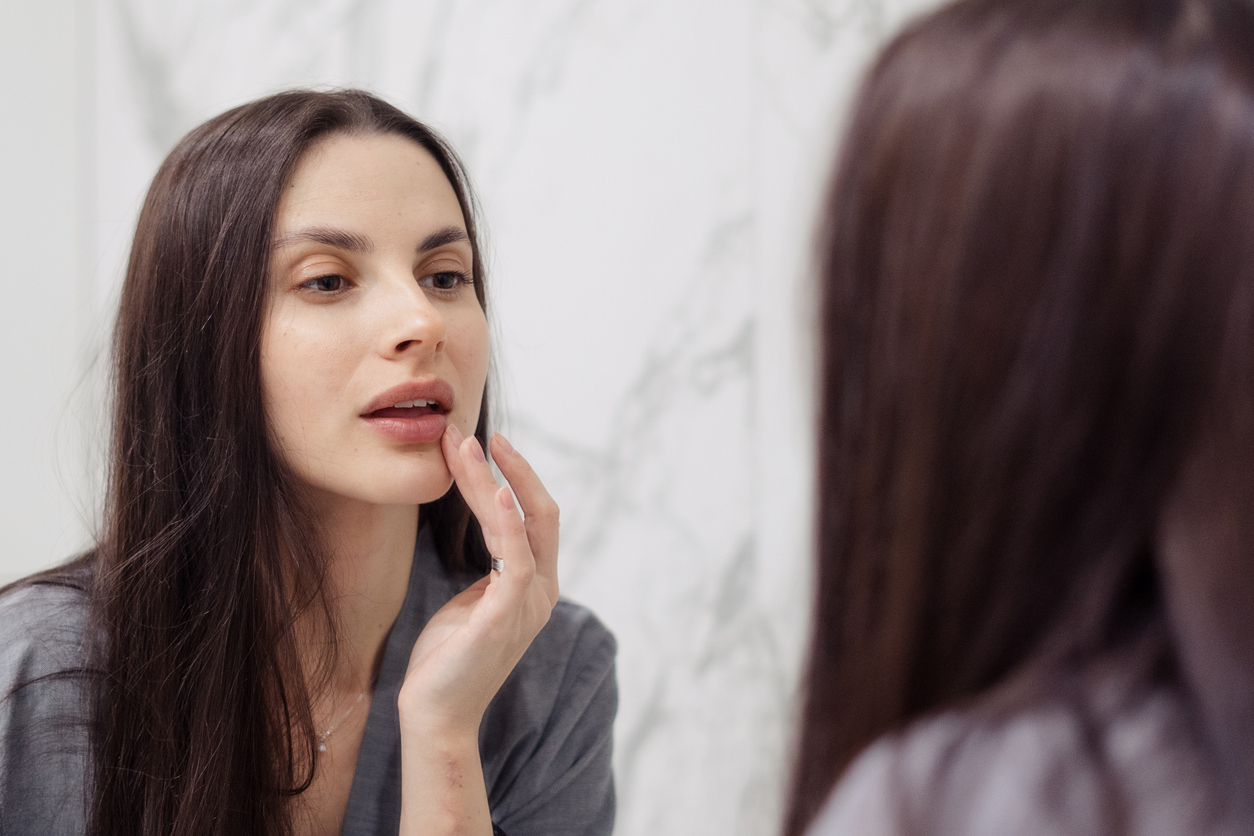 Woman examining her lips in a mirror.