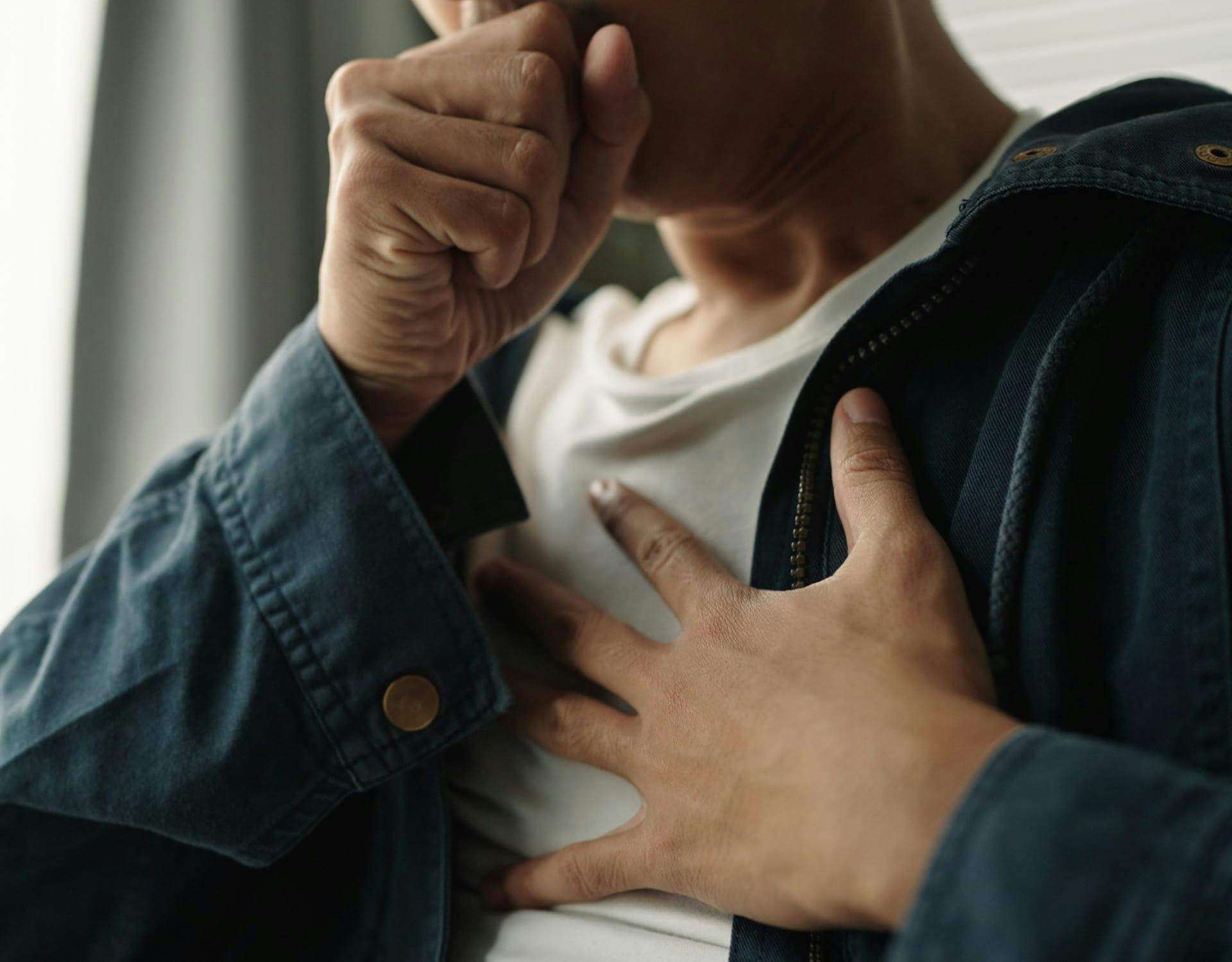 person coughing holding their chest