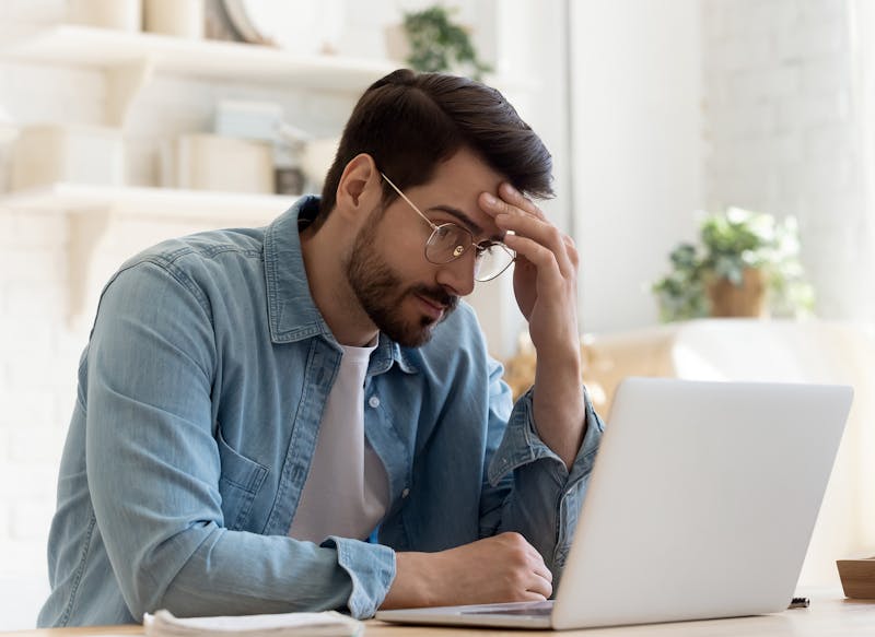 upset man looking at a laptop
