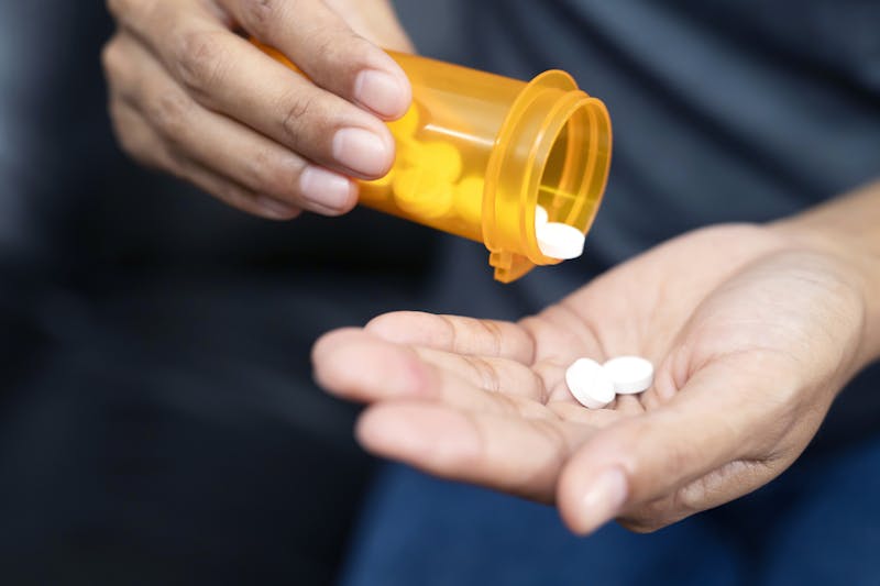 Person pouring pills into their hand