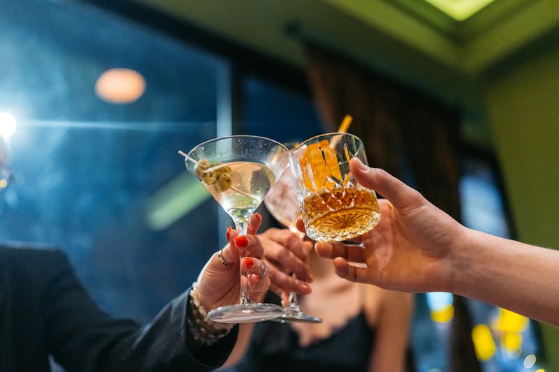People holding up drinks at a bar