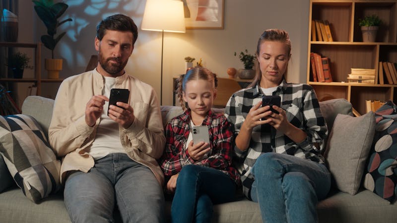 family using mobile phones on couch
